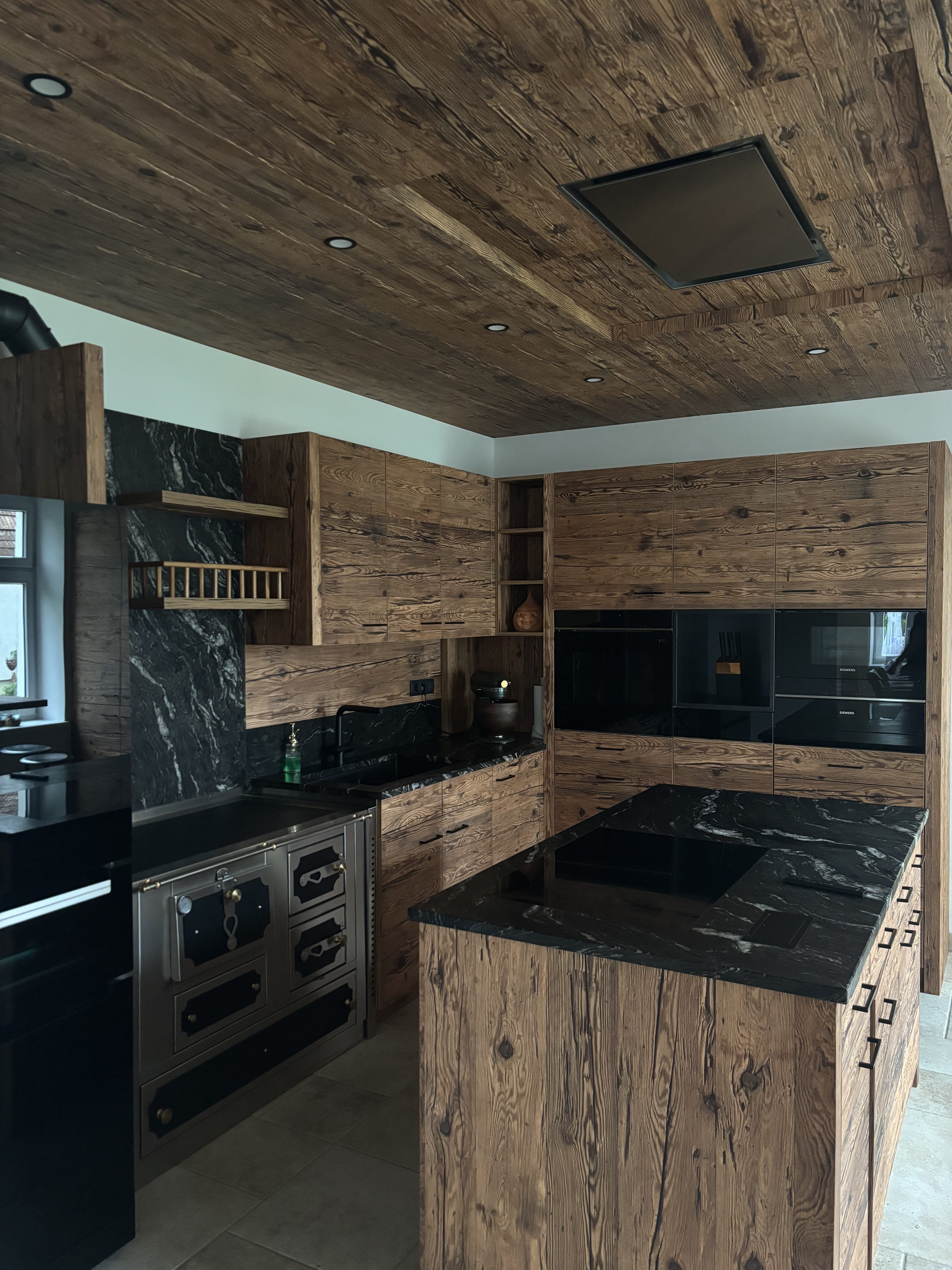 Moderne Küche mit Holzverkleidung, schwarzem Granit und integriertem Herd.